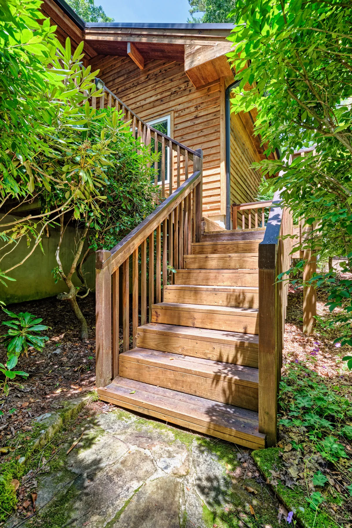 Captured from the entrance, this image draws viewers in with wooden stairs leading up to the chalet, surrounded by lush greenery. The approach is inviting, emphasizing the sense of arrival at a secluded, peaceful retreat ideal for professional groups.